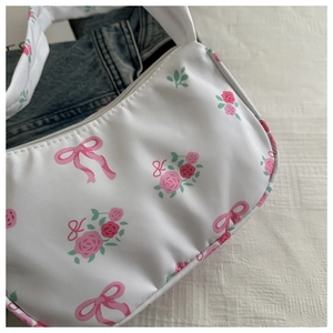 Close-up of white floral underarm bag with pink roses and ribbon bow print