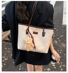 Close-up of cream leather tote bag with teddy bear charm and fashion logo tag