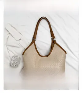 Detail of hand-woven leather tote bag with contrasting brown straps on white fabric