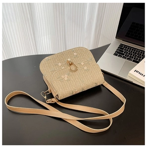 Detailed view of straw crossbody bag featuring floral embroidery and gold metal clasp