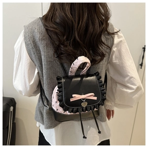 Close-up of pink and black lace bow backpack with a silver heart pendant detail