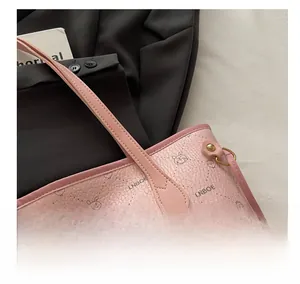 Détail des coutures du cabas rose, texture cuir litchi et boucle en D métallique
