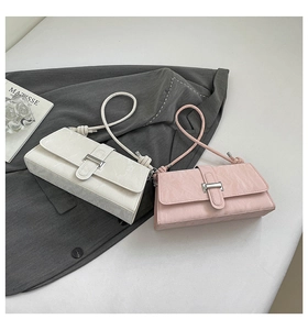 Detail of minimalist baguette bags in cream and pink showing textured wrinkled leather finish