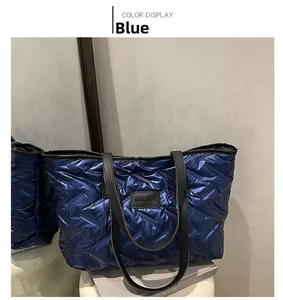 Detail view of blue quilted tote bag with metallic finish and black logo patch