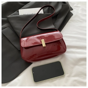 Close-up of retro dark red patent leather bag with gold buckle on a grey suit