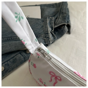Detailed close-up of a white canvas bag with pink bow floral patterns and silver zipper
