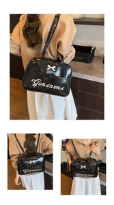 Detail of black patent leather travel bag showing bow decoration and embroidery