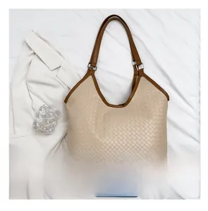 Detail of woven faux leather texture and brown strap on large beige tote bag