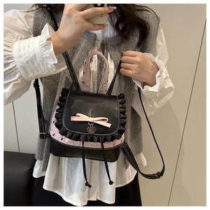 Detail of cute polka dot backpack with pink bow and heart pendant on black ruffled flap