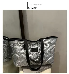 Detail of silver quilted tote bag with V-shaped stitching and black leather handles