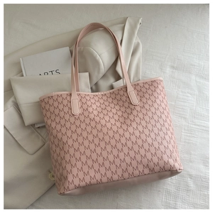 Close-up of pink tote bag with M-pattern texture placed on a beige blazer and art book
