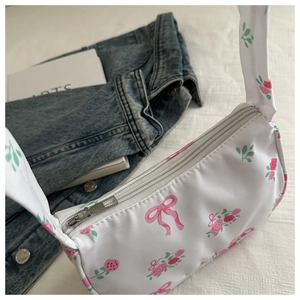Detail of floral canvas shoulder bag featuring pink roses and secure silver zipper closure