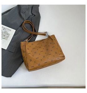 Detail of caramel brown faux leather handbag featuring letter and cartoon animal print