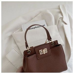 Close-up of litchi texture leather and golden twist lock on dark brown handbag