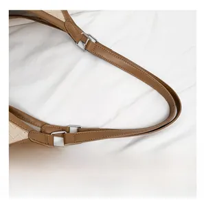 Detail of brown leather strap with fine stitching and silver square metal ring connector