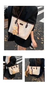 Detail of cream textured leather tote bag with brown trim and plush bear charm decoration