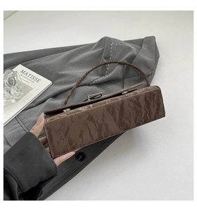 Detailed shot of dark brown wrinkled faux leather shoulder bag with silver buckle
