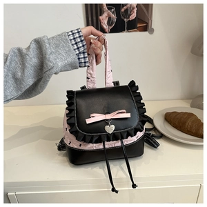 Détail du sac noir et rose avec bordure à volants et pendentif cœur dans un cadre cosy
