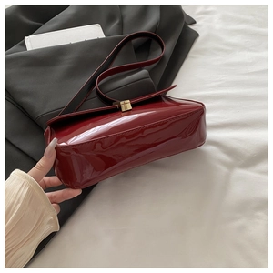 Detail of a vintage dark red patent leather baguette bag with a gold metal clasp buckle
