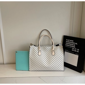 Detail of monogram tote bag with cream canvas and gray M pattern for daily commute
