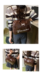 Detail view of brown patent leather backpack with white bow and cursive embroidery