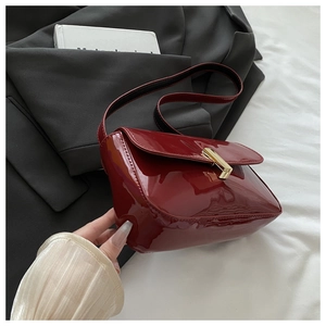 Close-up of a burgundy patent leather shoulder bag with a stylish gold metallic buckle