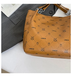 Detail of brown litchi pattern leather tote with cartoon print and chain strap