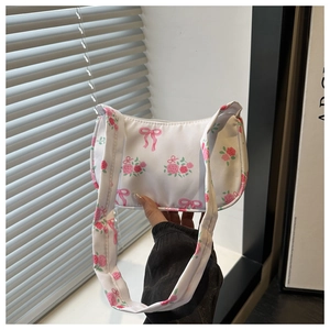 Close-up of white underarm bag with pink rose clusters and red bow prints