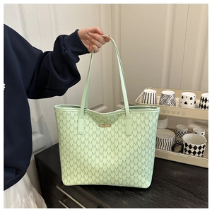 Detail of mint green tote bag with M-pattern monogram print and gold metal plaque