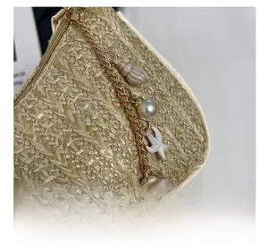Détail macro du sac en paille beige avec chaînes dorées, étoiles de mer et perles