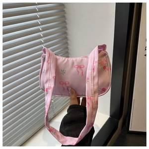 Close-up of pink canvas underarm bag featuring ribbon bows and floral patterns