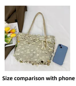 Detailed shot of sequin tote bag with pearl bow pendant next to a smartphone for scale