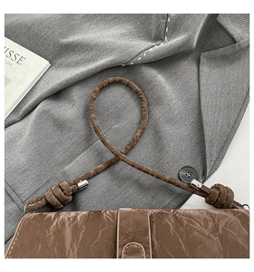 Detail of brown pleated shoulder bag with unique knotted rope strap and silver hardware