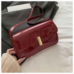 Detail of burgundy patent leather shoulder bag with elegant gold metal lock buckle