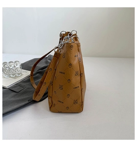 Close-up of brown pebbled leather handbag featuring cartoon prints and silver metal rings