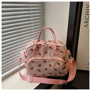 Close-up of pink corduroy tote bag featuring strawberry prints and front zipper pocket