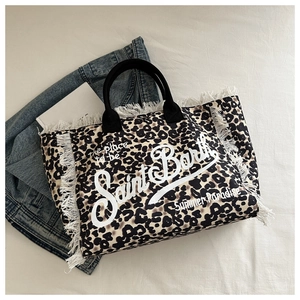Detailed close-up of leopard print canvas tote bag featuring raw fringe edges and text
