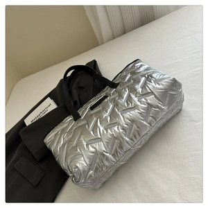 Close-up of silver quilted handbag with textured metallic finish and black leather straps