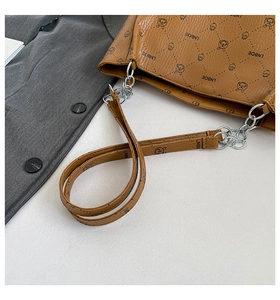 Close-up of brown embossed leather handbag showing interior zipper and metal chain strap