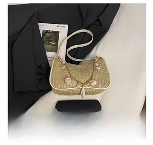 Détail du sac croissant en paille avec breloques perles, coquillages et chaîne dorée