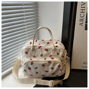 Detail of strawberry corduroy lunch bag with zip pockets and adjustable strap