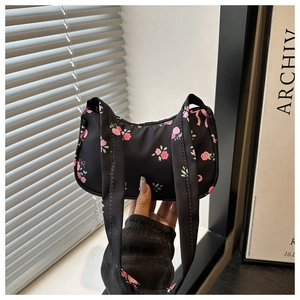 Detail of floral underarm bag showing pink rose print on black fabric with twin handles