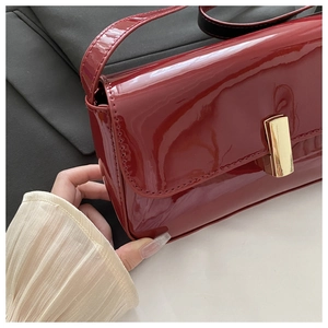 Close-up of vibrant red patent leather handbag with elegant gold magnetic buckle clasp
