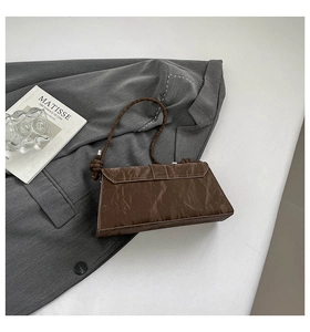 Detailed view of brown marble texture baguette bag with knotted braided shoulder strap