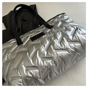 Detail of silver metallic quilted tote bag with Y-shaped stitching and black strap