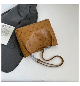 Close-up of brown pebbled leather tote featuring bear pattern and silver chain strap