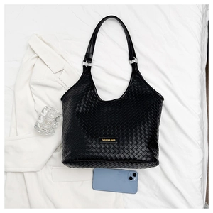 Close-up of black woven hobo bag with a phone for size reference on white fabric