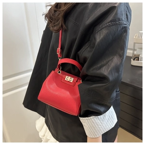 Detailed view of red lychee grain leather mini bag with gold twist lock on female model