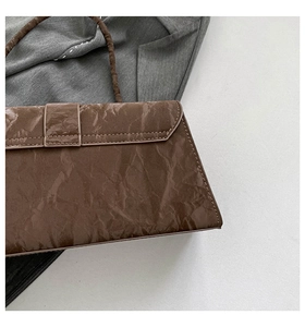 Close-up of brown textured leather shoulder bag showing unique pleated pattern details