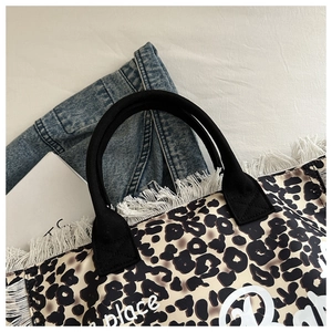 Close-up of leopard print tote bag with white fringes and Barbie-style typography print